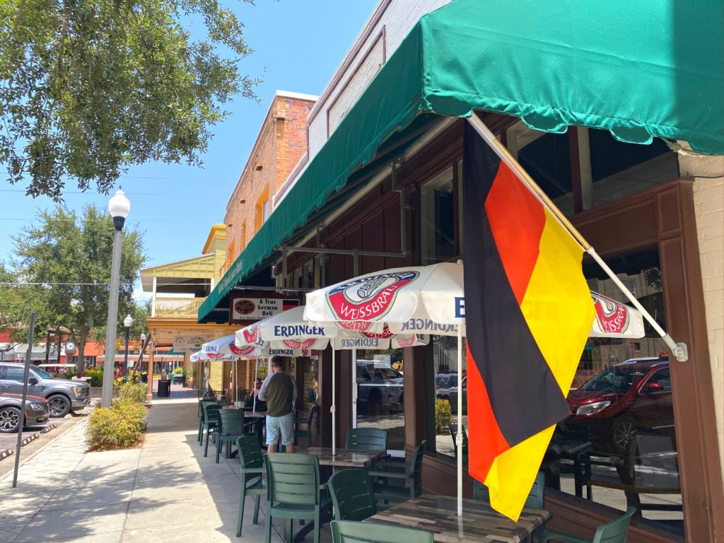 exterior of magnolia square market with german flag hanging in front of the entrance and outdoor seating