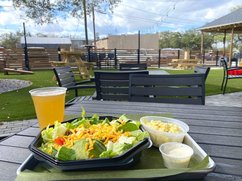 Salad and beer at outdoor table at The Yardery in Sanford