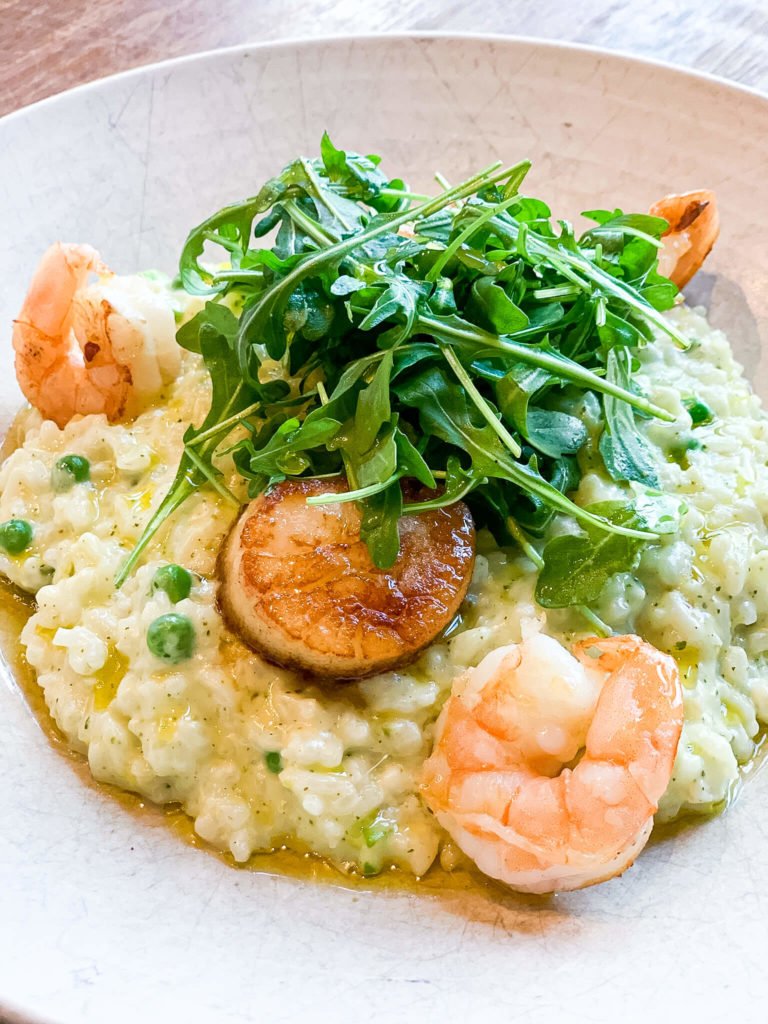 EASTER SPRING PEA AND PESTO RISOTTO with shrimp and scallop on a white plate