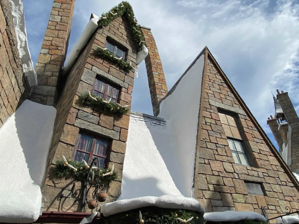 Garlands with ornaments that look like snitches from the game of Quidditch in the Wizarding World of Harry Potter adorn the window ledges and doorway of a Quidditch supply shop in Hogsmeade Village