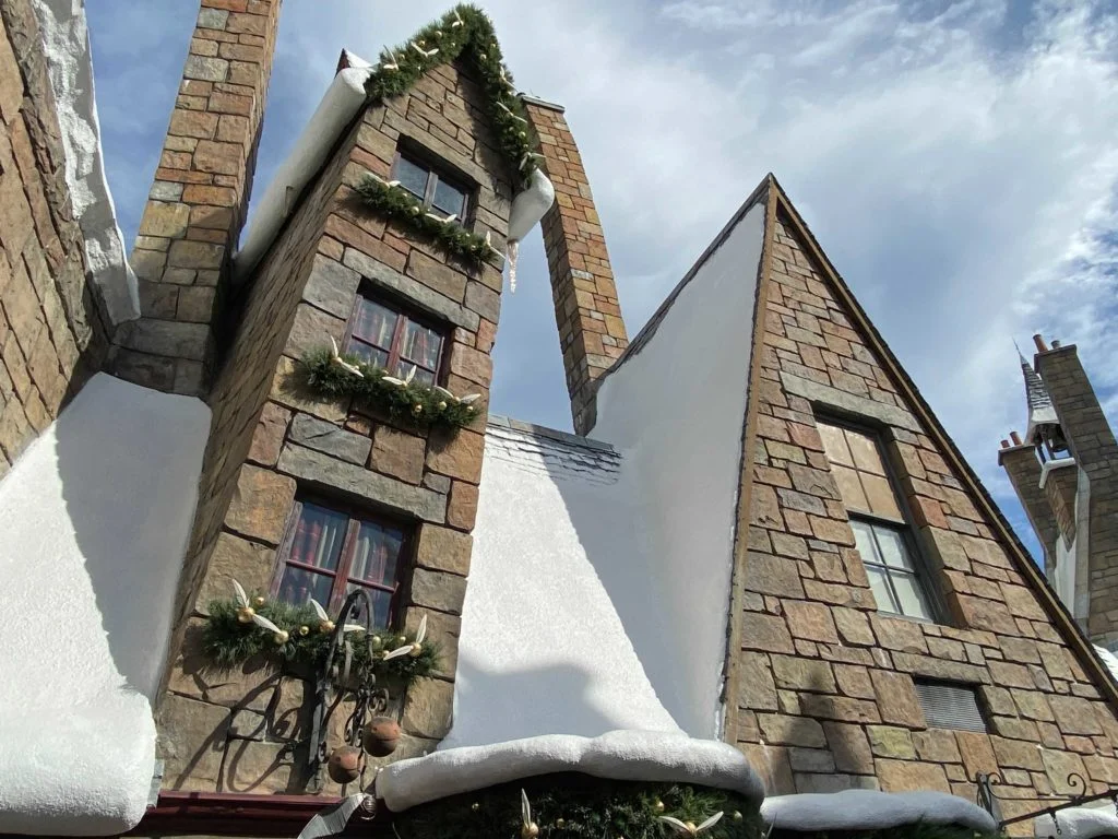 Garlands with ornaments that look like snitches from the game of Quidditch in the Wizarding World of Harry Potter adorn the window ledges and doorway of a Quidditch supply shop in Hogsmeade Village