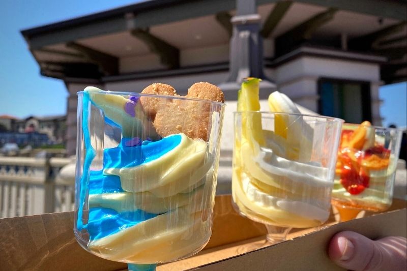 Disney Dole Whip Flight at Disney Springs close up with three clear plastic cups of swirled dole whip ice cream