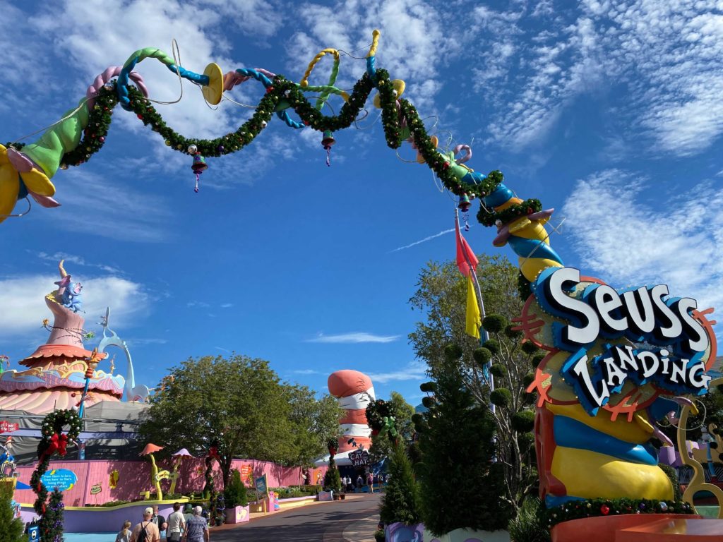 Green garlands with red and bright colored ornaments are draped around the Seuss Landing entrance sign at Islands of Adventure. 