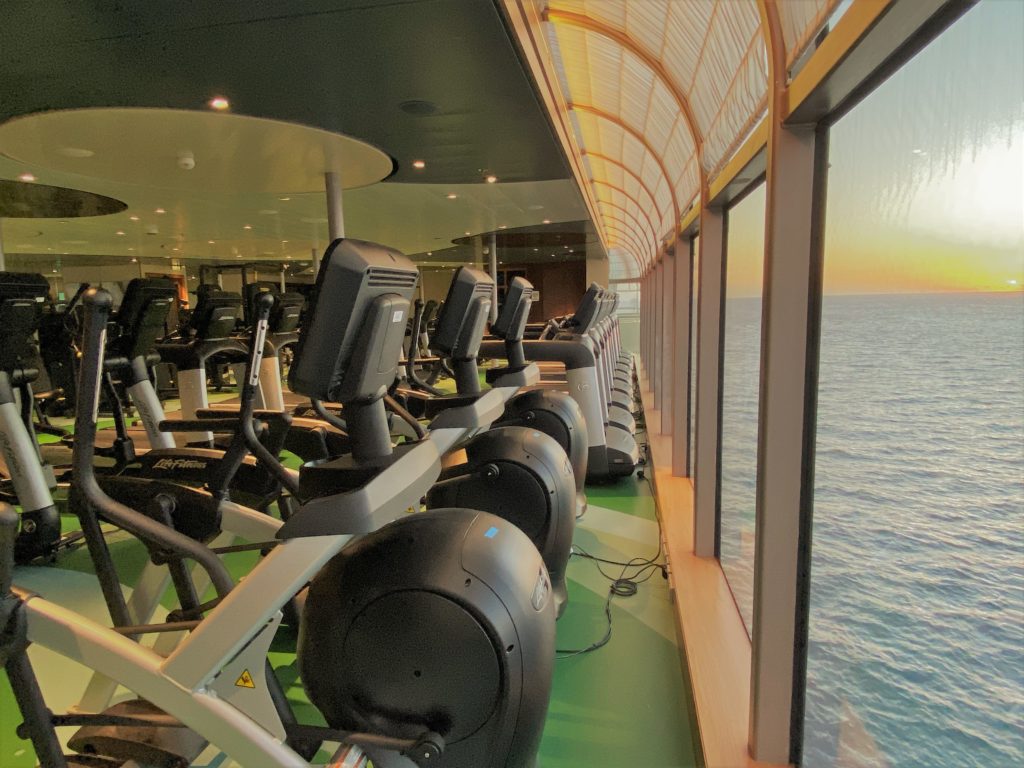 Fitness center aboard Disney Cruise Line in the early morning with elliptical machines and treadmills overlooking the ocean