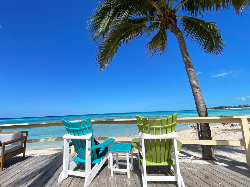 Lounge seating at Castaway Air Bar on Serenity Bay adults only beach features a wooden deck and views of tranquil ocean water 