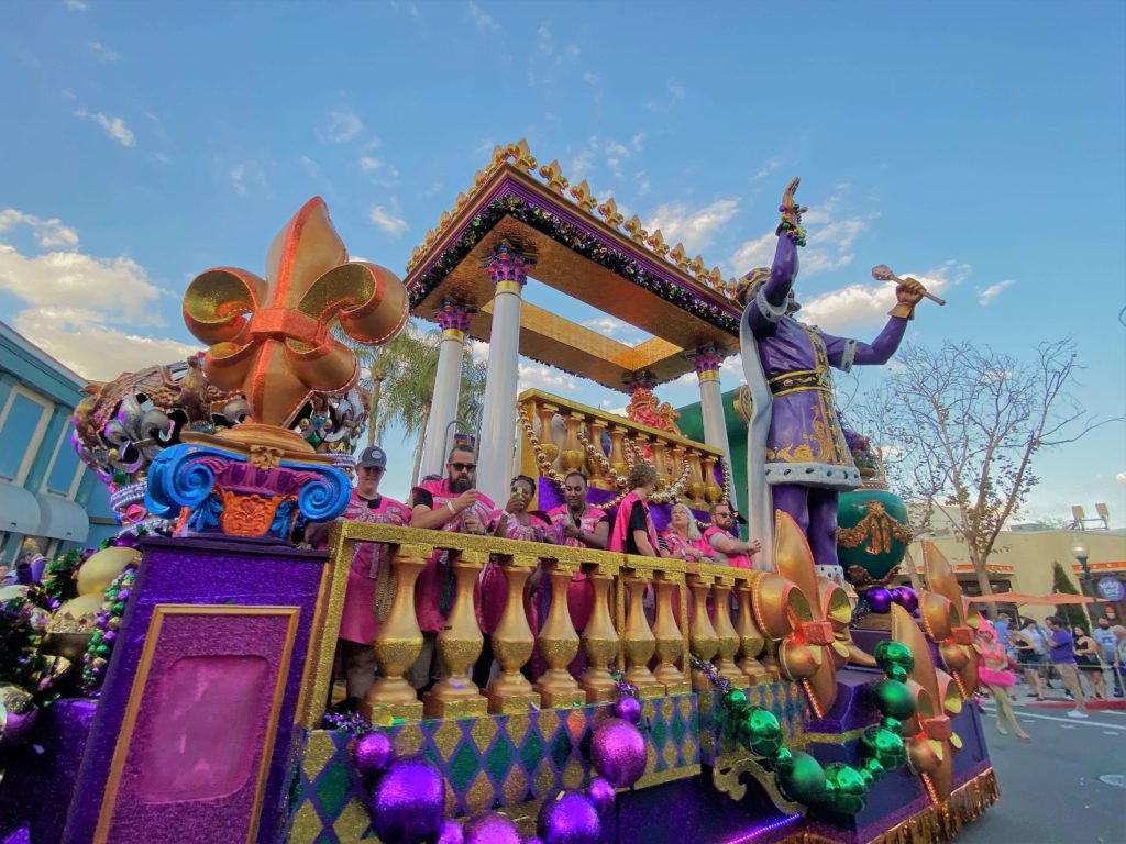 Park guests Ride a Float in Universal's Mardi Gras Parade and toss beads