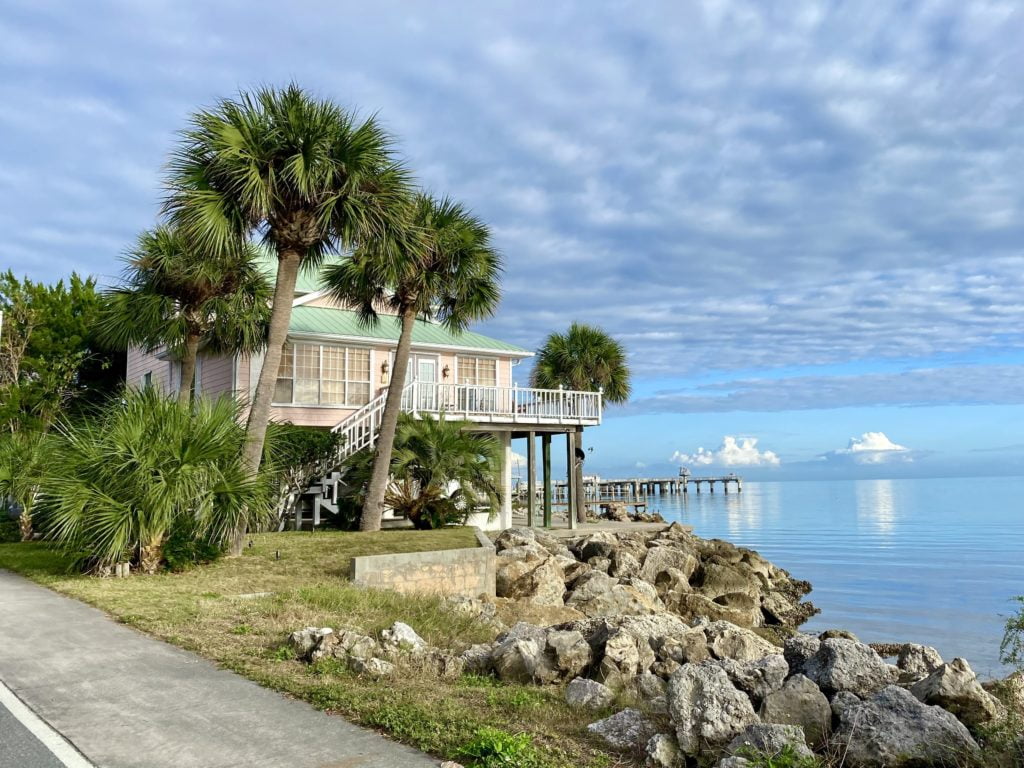 Cedar Key Florida - Coin de G Street et 2nd Street avec l'eau du golfe, des rochers, des palmiers et une maison tropicale