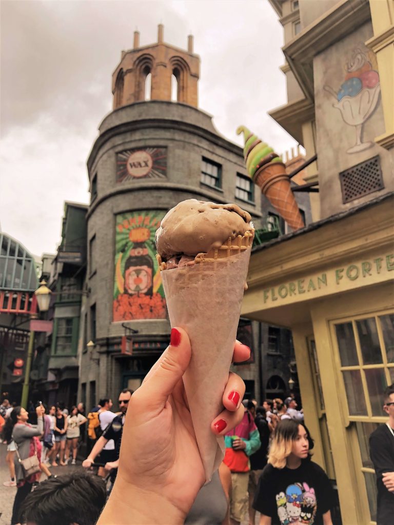 holding up an Florean Fortescue's Ice Cream at Diagon Alley into the air in front of the colorful facades