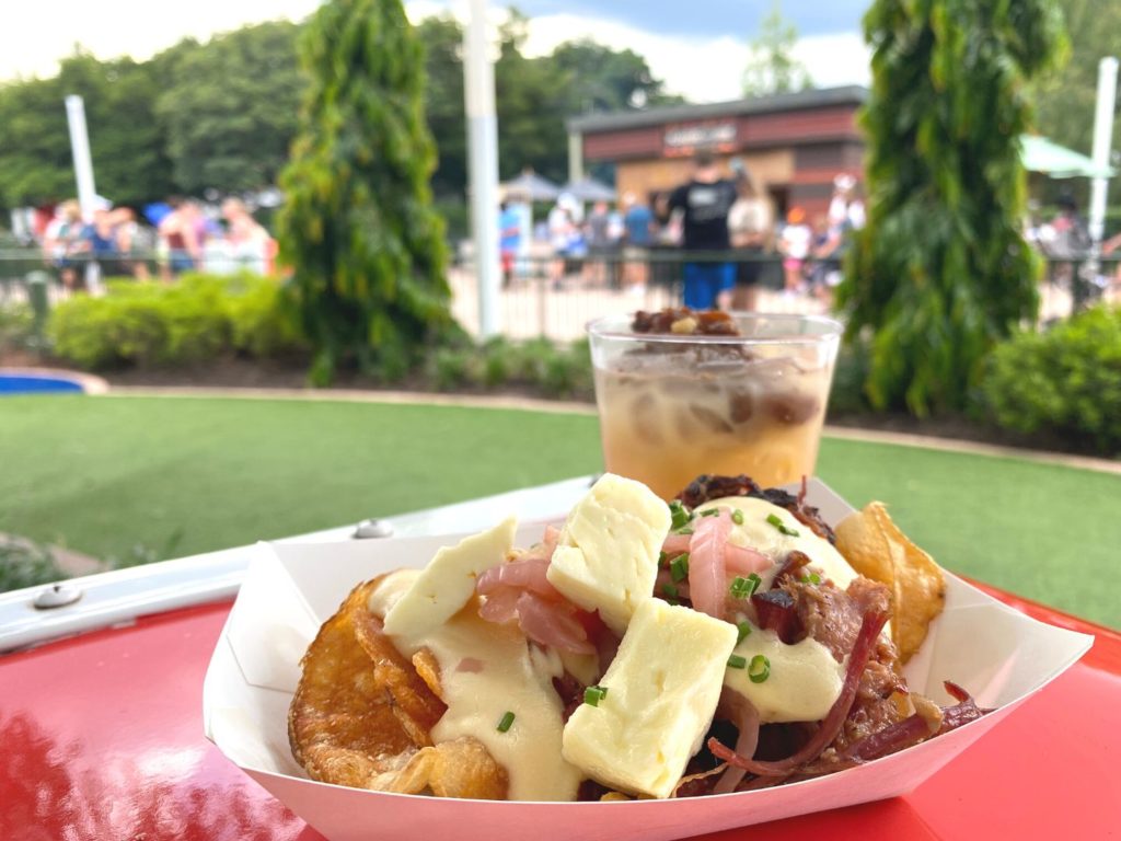 Corned Beef with Swine Brine Cocktail at 2022 Epcot Food and Wine Festival with Flavor from Fire booth in the background