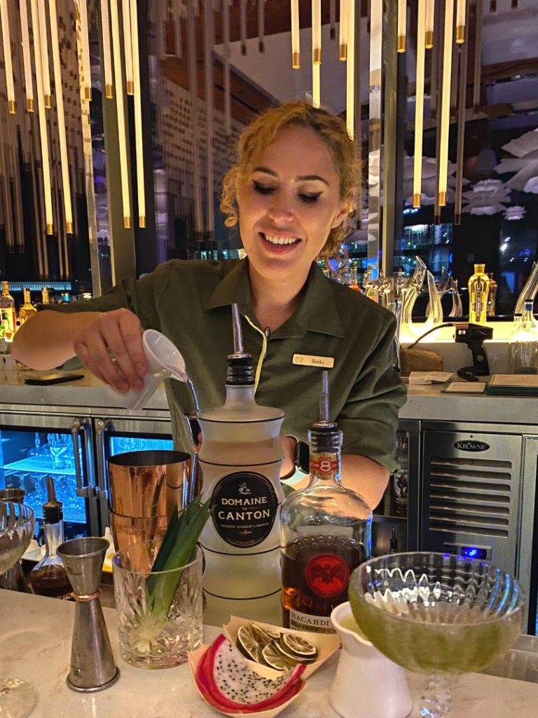 a bartender pours spirits into a cocktail shaker during a mixology experience at the Haven Lounge