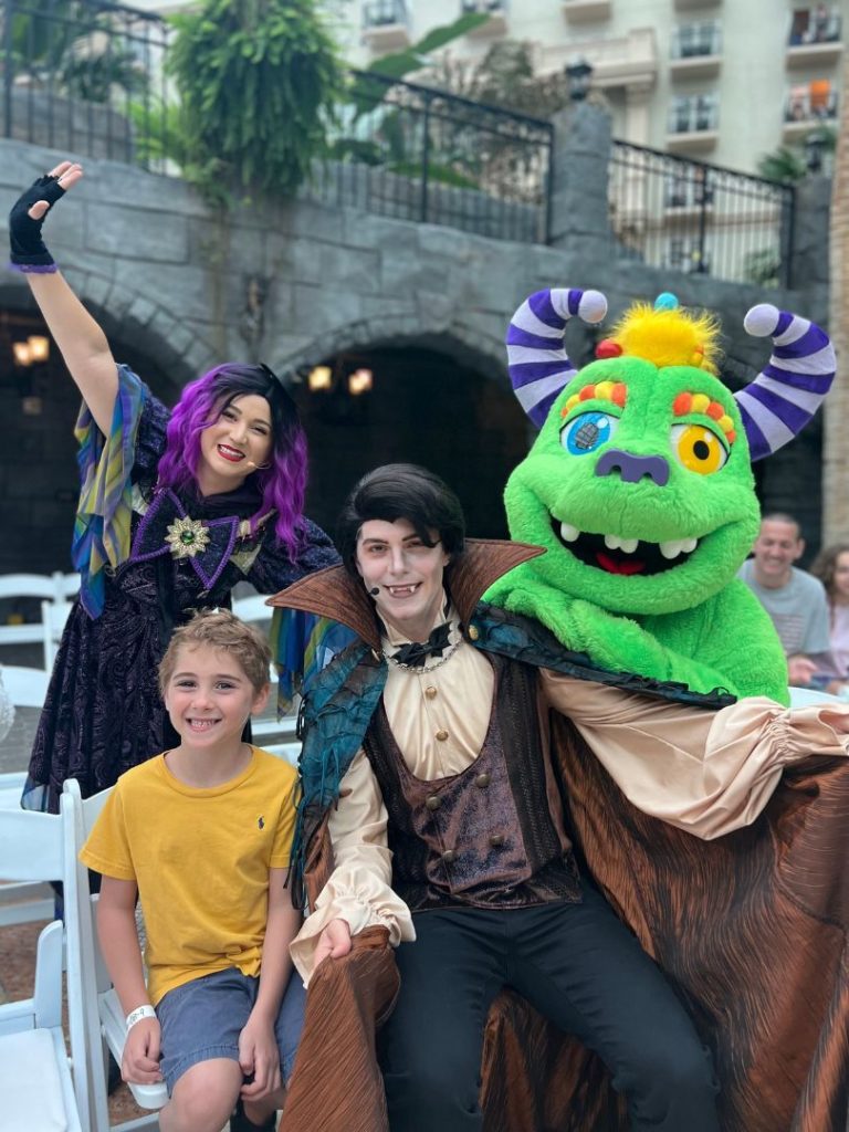 A young child poses with 3 characters during Goblins and Giggles Weekends at Gaylord Palms Orlando 