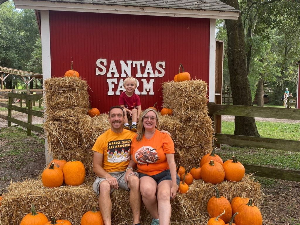 a family of 3 poses at Santas Farm Pumpkin Patch near Orlando