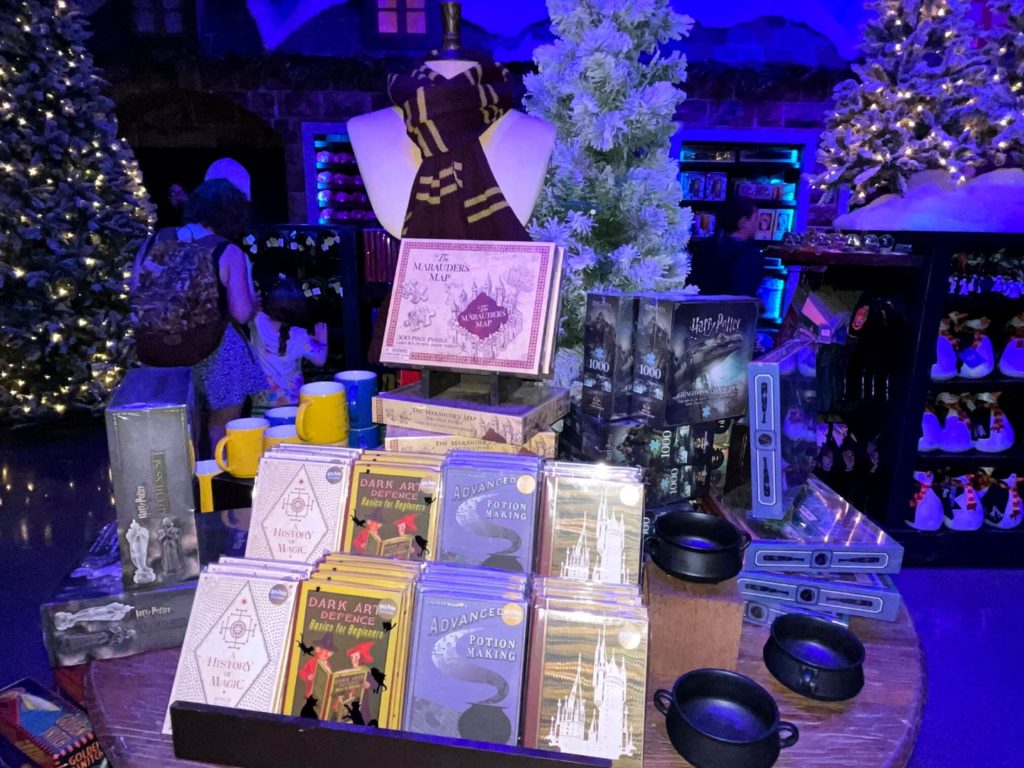 Hogsmeade Village Room at Universal's Holiday Tribute Store 2022 with Harry Potter themed books and merchandise on display in a themed room with special lighting