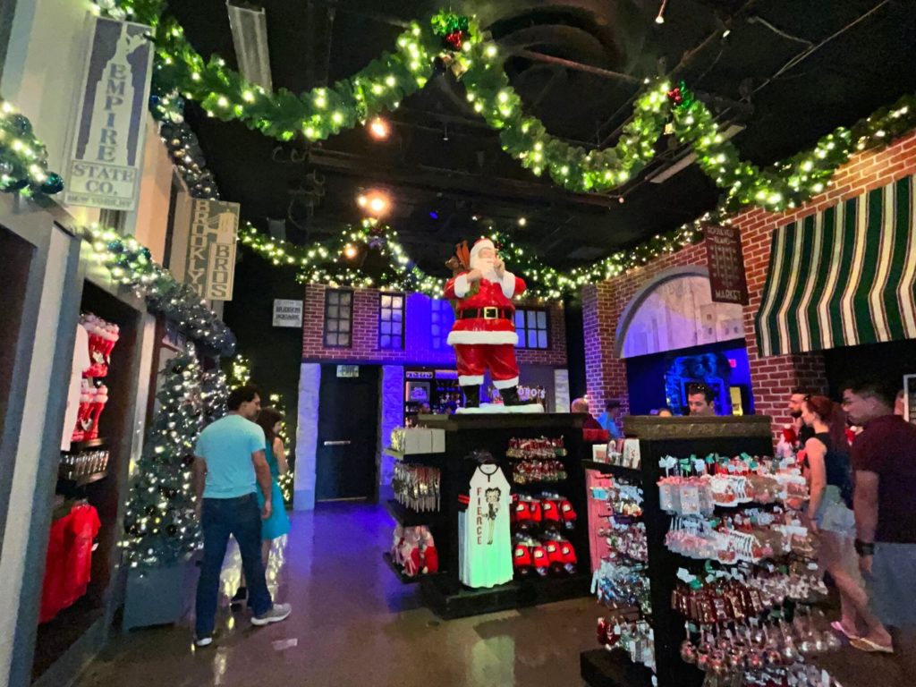 New York City Christmas Room at Universal's Holiday Tribute Store 2022 - with a classic Santa Claus statue in the center of the room and garland with white christmas lights hanging on the ceiling
