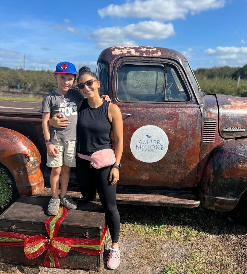 Alayna Curry stands with her young son in front of an old pick up truck one of the Photo opportunities during strawberry picking at Amber Brooke Farms Eustis - Alayna Curry