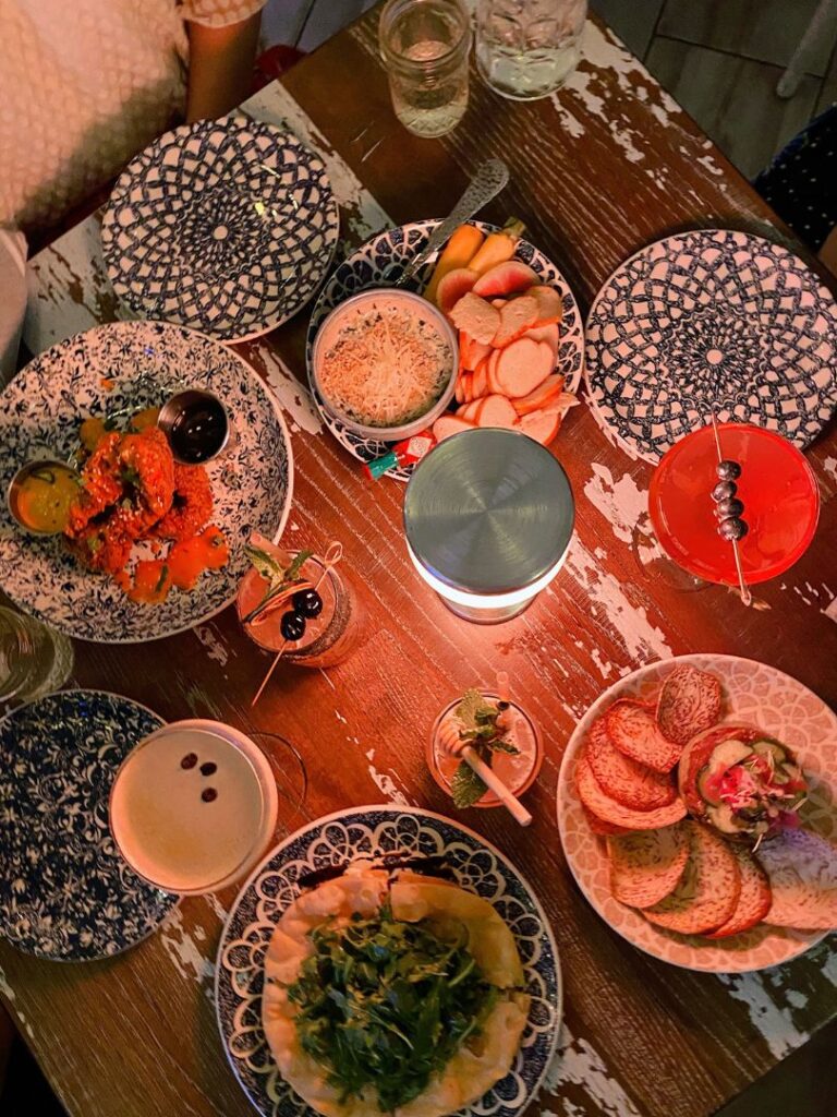 multiple appetizers and cocktails on a table for Galentine's Day in Orlando at The Hampton Social -